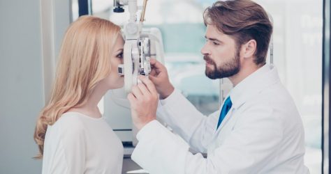 Health care, medicine, eye sight and technology concept. Side profile photo of brunet bearded optician checking blond`s lady patient intraocular pressure at eye clinic